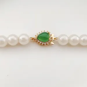 Close-up detail of green gemstone pearl necklace clasp, micro-set zircon gold fishhook connector.