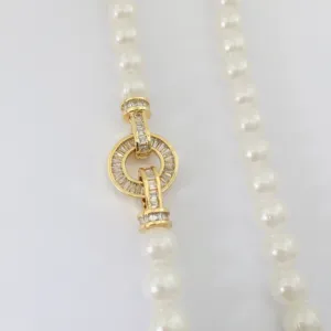 Close-up detail of DIY pearl necklace gold clasp with baguette stones and circular lock design.