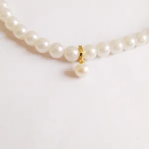 Elegant pearl necklace detail showcasing a gold plated clasp and hanging pearl pendant accessory.