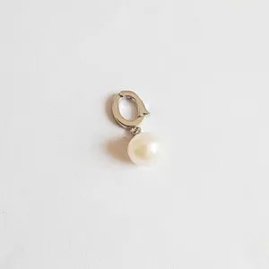 Closeup detail of a DIY pearl charm clasp pendant hook, silver metal jewelry finding component.