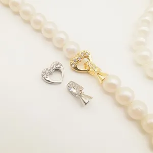 Pearl necklace clasp detail showing gold and silver heart zirconia jewelry connector.