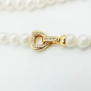 Vue détaillée d'un fermoir en forme de cœur plaqué or avec zircone pour collier de perles.