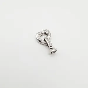 Détail fermoir perle cœur zircon, vue rapprochée composant accessoire bijoux argenté.