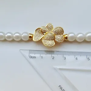 Detailed shot of DIY pearl necklace clasp with sparkling zirconia gold floral charm and pearls.