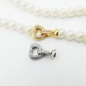 Vue détaillée du fermoir de collier en perles avec zircon en coeur, apprêts dorés et argentés.