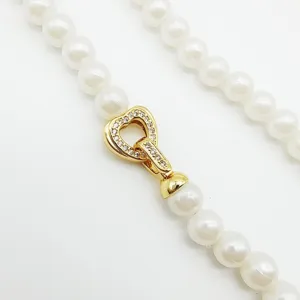 Gros plan détaillé d'un fermoir de collier et bracelet en perles avec cœur en zircone.