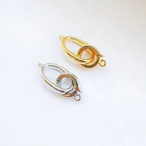 Close-up detail of DIY metal jewelry clasps, dual-ring connector in gold and silver.