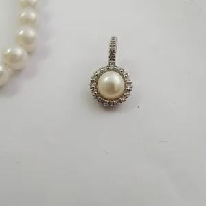 Detailed shot of micro-pave rhinestone pearl pendant clasp, delicate jewelry accessory.