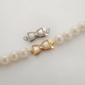 Primo piano di chiusure per collane di perle a fiocco in oro e argento con madreperla.