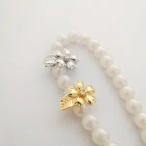 Detailed view of DIY pearl necklace clasp with gold and silver flower leaf design charms.