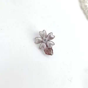 Close-up detail of DIY flower and leaf necklace clasp, brushed metal finish with crystal center.