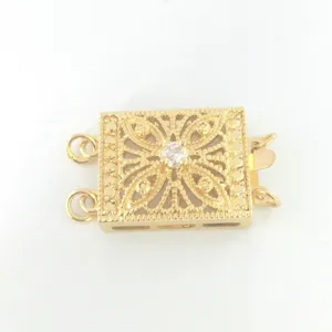 Close-up of a gold-plated multi-row jewelry clasp with vintage filigree and central stone.