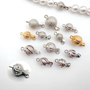 Close-up view of various metallic spherical jewelry clasps, showcasing matte, sparkle and carved details.