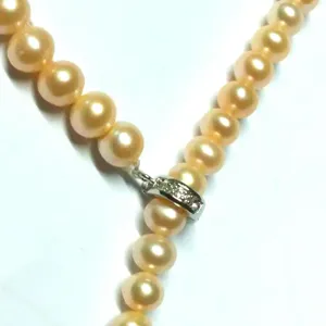 Close-up detail of peach pearl necklace with sparkling micro-pave front universal clasp.