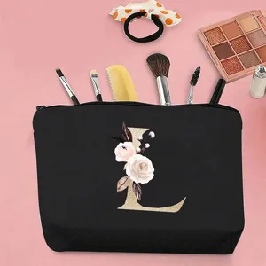 Elegante bolso de maquillaje de lona negra con letra L dorada y estampado floral.