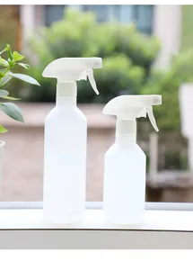 Detail shot of white plastic spray bottles on a windowsill, ideal for home cleaning and watering.
