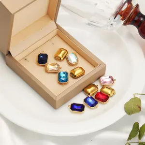 Close-up of various colorful rectangular crystal and gold charms inside a beige jewelry box