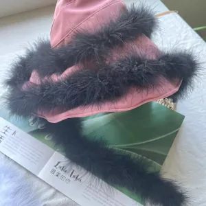 Pink bucket hat adorned with fluffy black feathers, stylish fuzzy design fashion accessory.