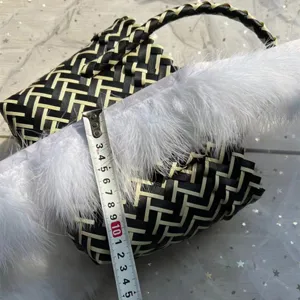 Detalle de bolso tejido en blanco y negro con ribete de plumas y cinta métrica.