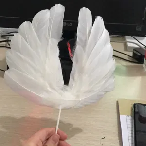 Vue détaillée de toppers de gâteau d'ailes d'ange en plumes blanches pour anniversaire.