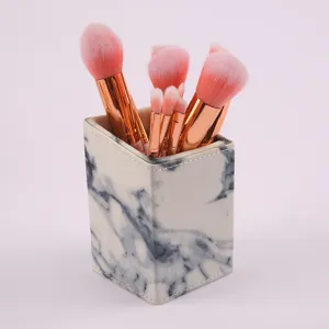 Detailansicht des Marmormuster-Make-up-Pinselhalters mit rosa Borsten und roségoldener Zwinge.