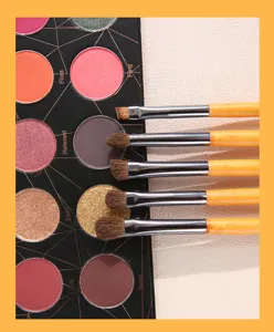 Detailed close-up of 5-piece makeup brush set with wooden handles next to colorful eyeshadow palette.