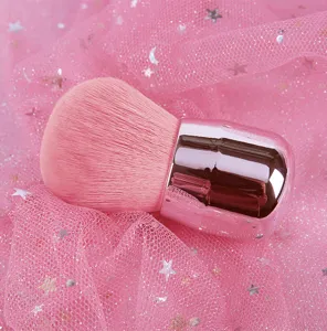 Detail van een zachte roze kabuki make-up borstel op glitterende sterren gaas stof.