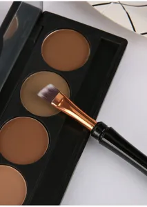 Vue détaillée d'un pinceau de maquillage biseauté posé sur une palette de contouring.