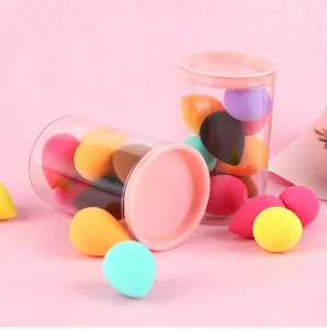 Detailshot van kleurrijke mini druppel makeup sponsjes in doorzichtige bakjes op roze achtergrond