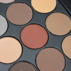 Gros plan détaillé d'une palette de fards à paupières nude aux teintes chaudes et neutres.