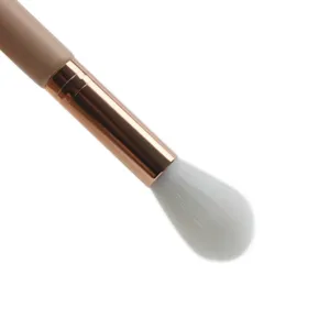 Close-up detail of soft animal hair highlighter makeup brush with elegant rose gold ferrule.