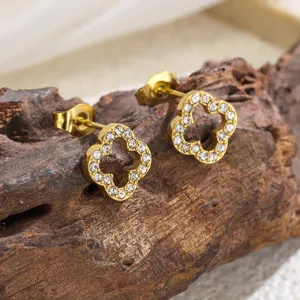 Close-up detail shot of gold-plated clover stud earrings sparkling with clear rhinestones.