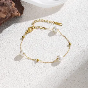 Squisito dettaglio di catena di perle in acciaio al titanio con delicate maglie dorate.