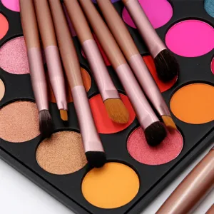 Close-up detail of professional makeup brush set with colorful eyeshadow palette background.