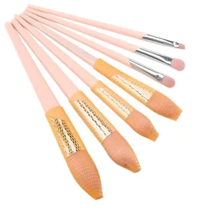 Close-up detail of soft pink makeup brush set with protective mesh on bristles for safety.
