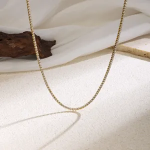 Detail view of a delicate gold-colored tennis necklace featuring sparkling stones on fabric.