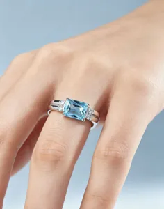 Nahaufnahme des eleganten blauen Edelsteinrings mit kleinen Zirkonia Steinen am Finger.