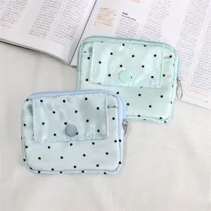Close-up detail of the mini polka dot coin purse with flap pocket and secure zipper closure.