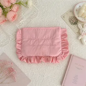 Detailansicht der süßen rosa Kosmetiktasche mit Rüschen, zarter Stickerei und weicher Stofftextur.