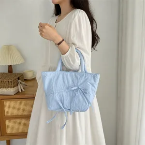 Dettaglio borsa shopper plissettata azzurra, con graziosi fiocchi e ampio design per il commuting.