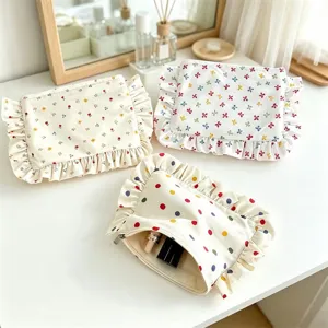 Detailed view of cute cosmetic storage bags with floral patterns and ruffled edges on white desk.