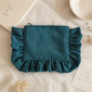Details of dark teal corduroy makeup pouch featuring elegant ruffled edge and secure zipper closure.