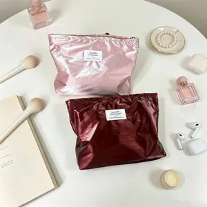 Dettaglio della borsa cosmetica impermeabile perlescente lucida con finitura metallica e corda.