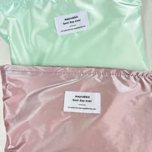 Dettaglio della borsa cosmetica impermeabile lucida con etichetta in tessuto raffinata.