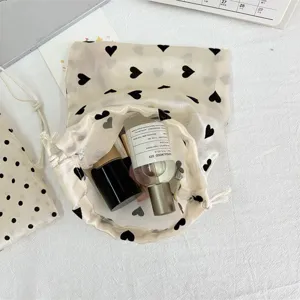 Detailed view of champagne sheer drawstring makeup storage bag with cute black heart pattern.