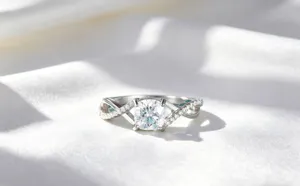 Detailansicht des silbernen Ringes im Kissenschliff mit gedrehtem Band auf Stoff.