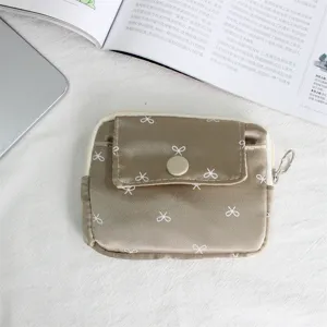 Detailed close-up of a stylish satin coin purse with cute bow print and handy zip closure.