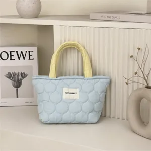 Quilted handbag detail view, light blue tote bag with yellow handle for daily commute storage.