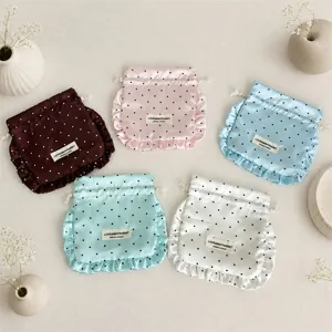 Satin polka dot drawstring pouch with ruffle detail, ideal for jewelry and earphone storage.