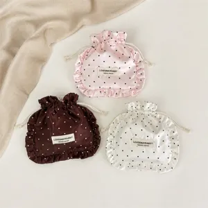 Satin polka dot drawstring storage bag with ruffle edge, detail view of cosmetic pouch.